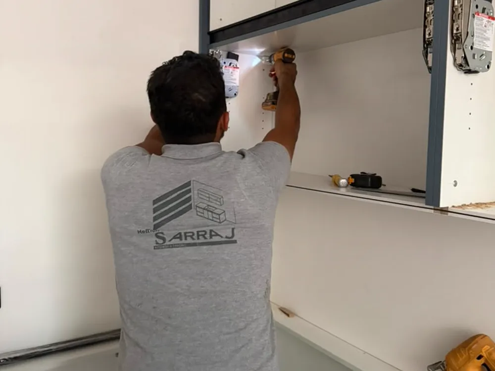 A Sarraj fitter drilling hinge plates into a wall unit